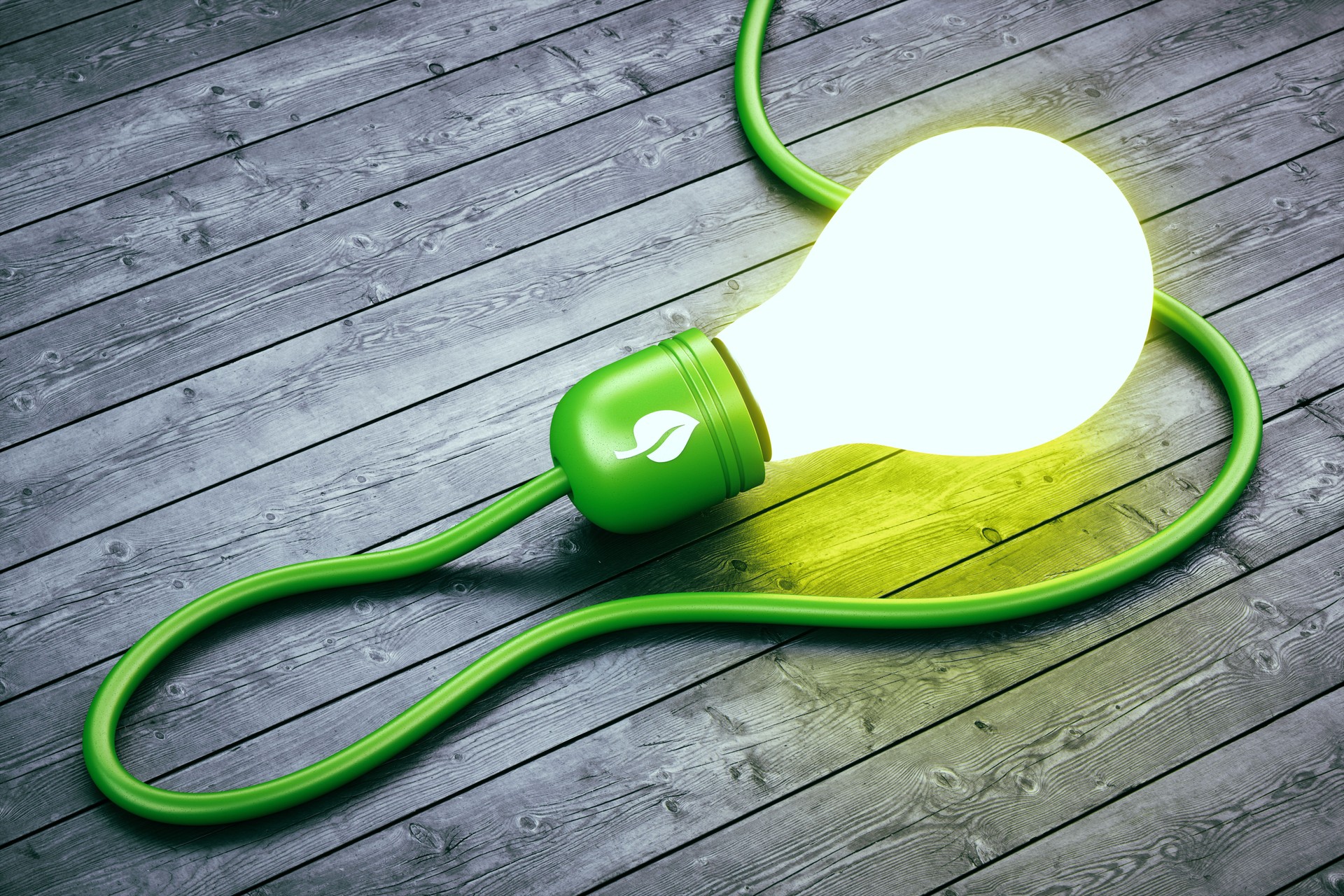 Glowing abstract green energy light bulb on hard wood floor